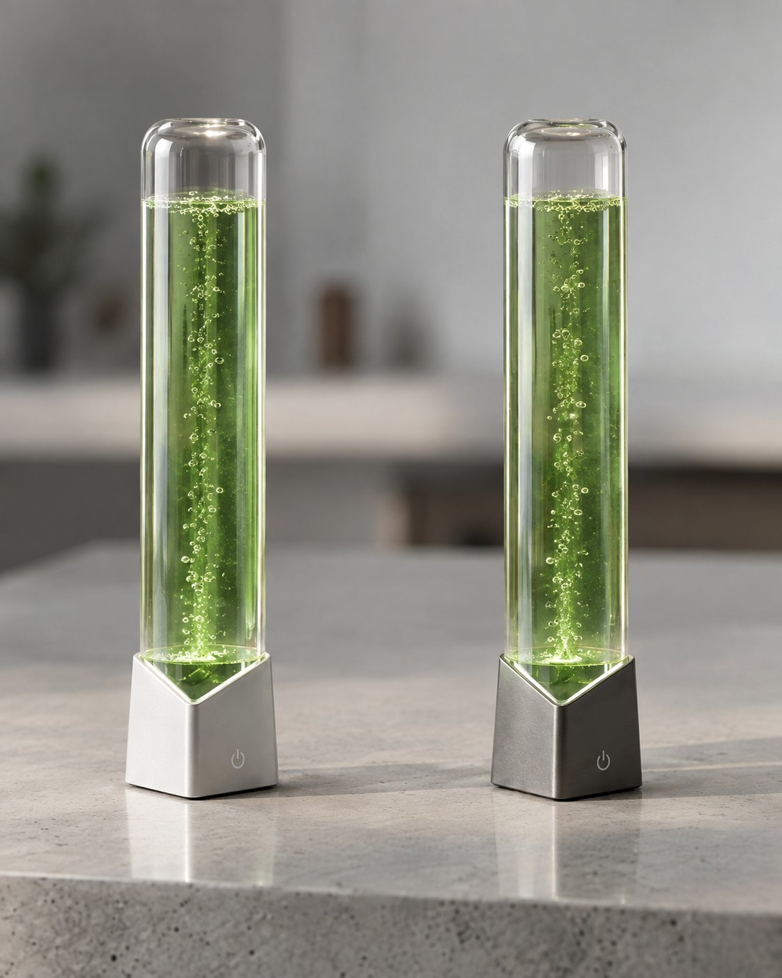 Two Vytrion microalgae columns on a stone counter, with anodized silver and space gray bases